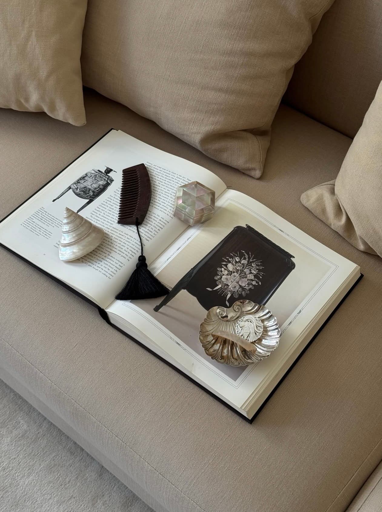 An open design book arranged with sculptural personal objects